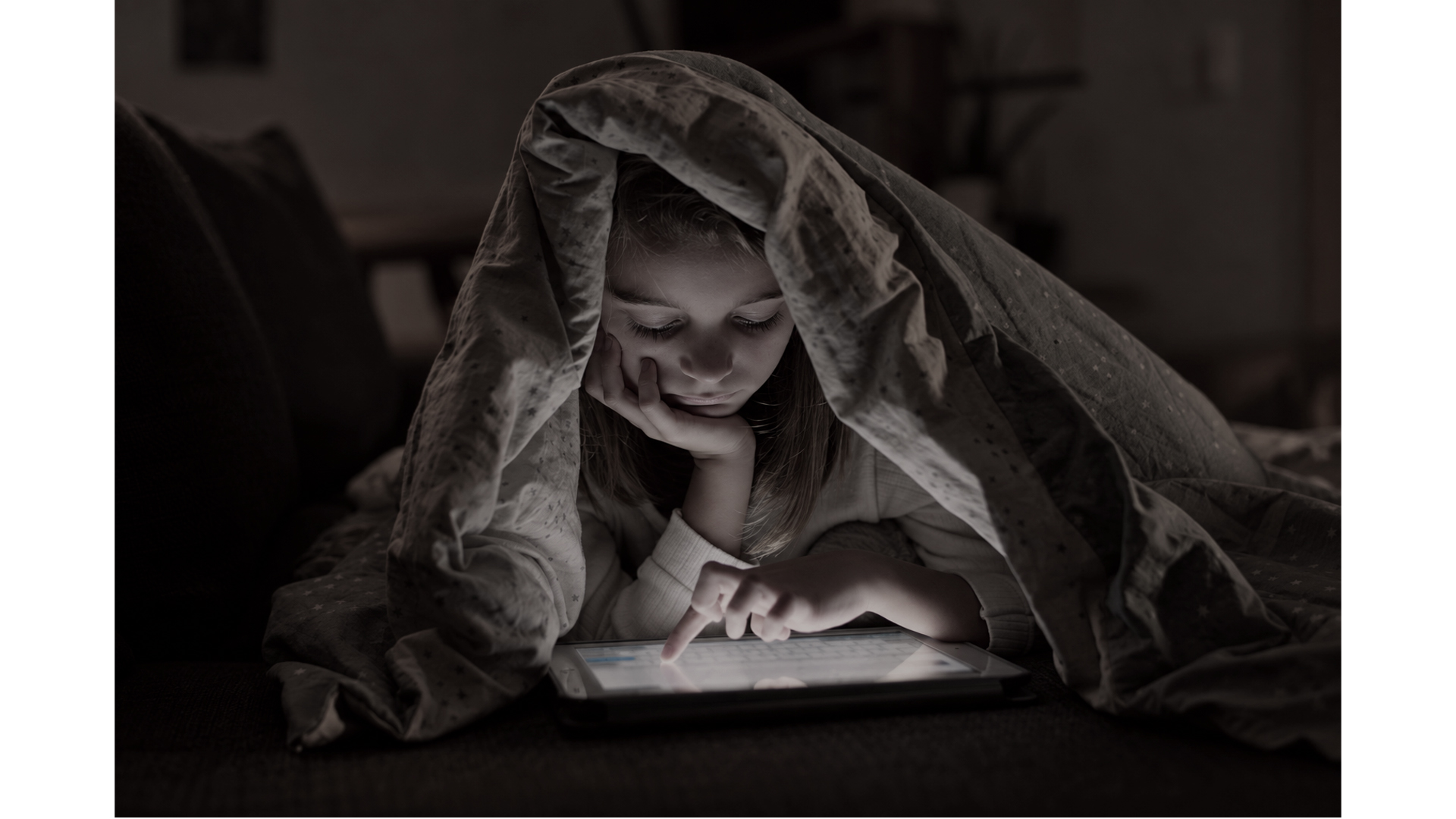 Menina usando um tablet sob uma coberta